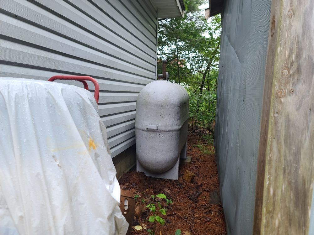 The side view of an oil tank installed between two residential homes